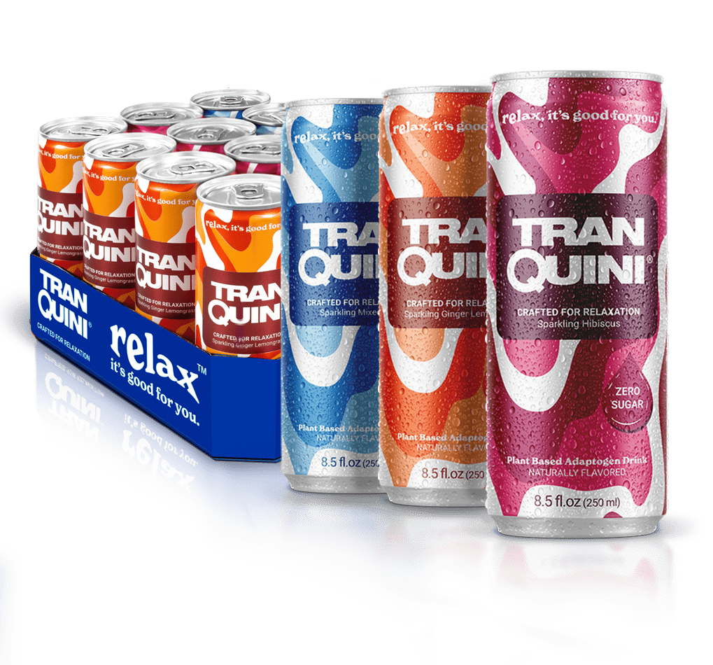 A shop display of Tranquini beverages features a 6-pack of cans in orange packaging alongside three tall individual cans in blue, pink, and red. Each can reads "relax, it's good for you" and comes in flavors like "Ginger Lemongrass," "Hibiscus," and "Zero Sugar.